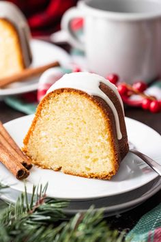 a bundt cake with white icing on a plate next to two cinnamon sticks