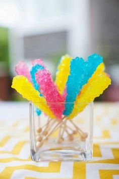 colorful candy sticks in a glass holder on a yellow and white tablecloth