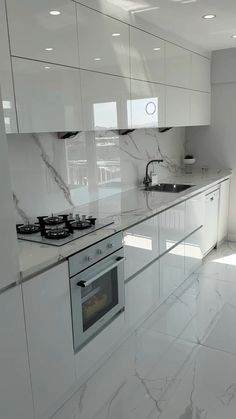 a kitchen with white cabinets and marble counter tops, along with a stove top oven