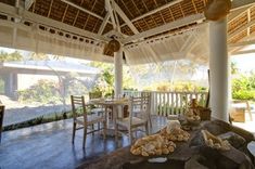 an outdoor dining area with tables and chairs under a thatched roof over looking the ocean