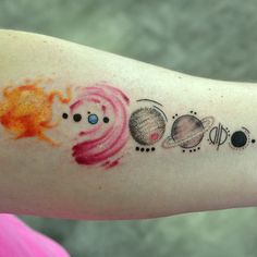 a woman's arm with different colored tattoos on her left arm and the sun, planets