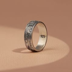 a wedding ring with an engraved date on the front and side, sitting on top of a table