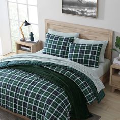 a green and white plaid comforter set on a wooden bed with two nightstands