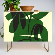 a potted plant sitting on top of a green cabinet next to a wooden bowl