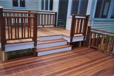 a deck with steps and railings in front of a house