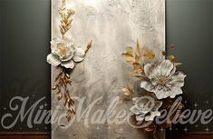 a painting with white flowers and gold leaves on the wall next to a wooden floor