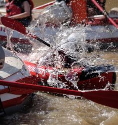 a group of people riding on the back of a red and white boat in water