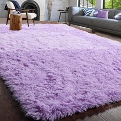 a living room with a purple rug on the floor and a fireplace in the background