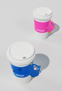 two coffee cups sitting next to each other on top of a white table with pink and blue designs