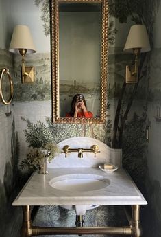 a bathroom sink with a mirror above it and lights on the wall next to it