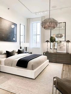 a large white bed sitting in a bedroom next to a tall mirror on the wall