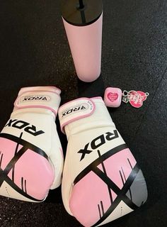 two boxing gloves and a pink cup on the ground