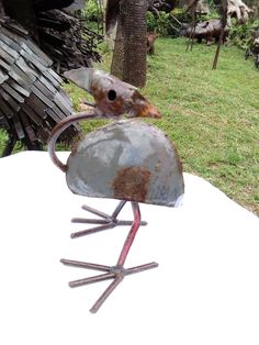 a metal bird sculpture sitting on top of a white table