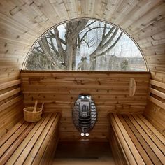 the inside of a wooden sauna with two benches and a round window on one side