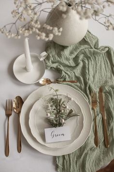 a table setting with place cards, silverware and flowers in a vase on it