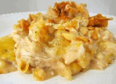 a white plate topped with macaroni and cheese covered in chicken sauce on top of it