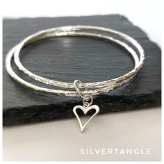 "Sterling silver round stacking bangles.  Lovely, classic round bangles with a hammered finish.  Accentuated with an open heart charm (approx. 10mm in size). Each bangle is made from solid 2.0mm round sterling silver wire and then hammered to give a great texture which really catches the light.  The bangles are then polished to give a shiny finish. The bangles are hallmarked by the Edinburgh Assay Office giving you peace of mind this is a genuine sterling silver (925 piece). The bangles also com Sterling Silver Stackable Bangle, Stackable Sterling Silver Bangle, Stackable Metal Bangle For Gift, Sterling Silver Stackable Round Bangle, Sterling Silver Heart Bracelet For Wedding, Sterling Silver Stackable Bangle For Anniversary, Round Wedding Bracelet With Heart Charm, Wedding Bracelet With Heart Charm, Everyday Bangle Bracelet With Heart Charm