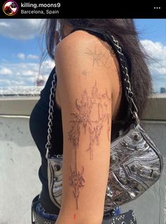 a woman with a tattoo on her arm is holding a purse and looking off into the distance