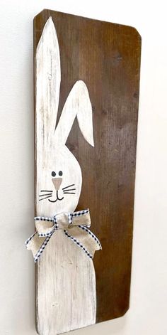 a wooden sign with a bunny painted on it's face and a bow tie around its neck