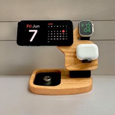 an apple watch and iphone charging station on a white counter top with a clock in the background