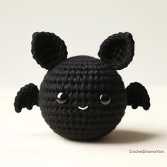 a crocheted black ball with eyes and ears is shown in front of a white background