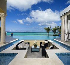 an outdoor living area with couches, tables and chairs near the water's edge