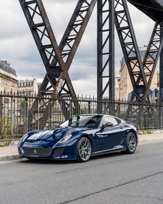 a blue sports car parked in front of a bridge