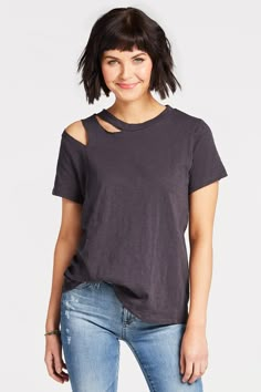 a woman in jeans and a t - shirt with cutouts on the shoulders is smiling