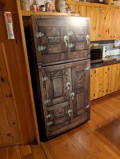 an old fashioned refrigerator in a kitchen with wood flooring and wooden cabinets on the wall