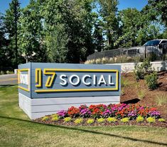 a large sign that says 7 / 7 social in front of some flowers and trees