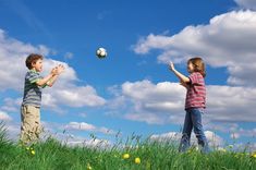 two children playing with a soccer ball in the grass on a sunny day stock photo