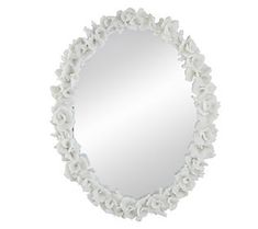 a white mirror with flowers on the edge and an oval shaped frame, hanging from a wall