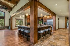 an open kitchen and dining room with wood flooring in the middle, along with large windows