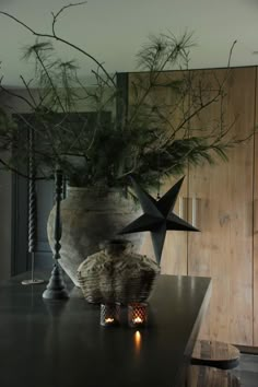 a vase with pine branches and candles on a table