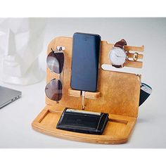 a cell phone and some glasses on a wooden stand with a laptop in the background