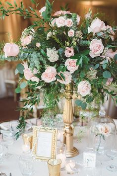 a vase filled with lots of pink flowers on top of a table next to plates and glasses