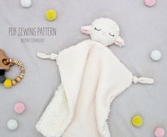 a white sheep wrapped in a blanket next to a wooden bead bracelet and earring