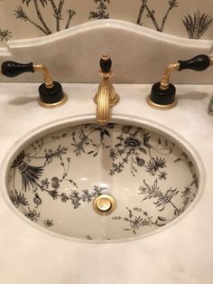 a white sink with black and gold faucets