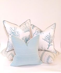 two blue and white pillows sitting on top of each other in front of a white wall