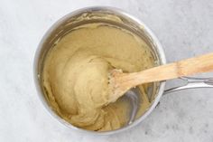 a wooden spoon in a metal pot filled with batter