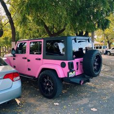 a pink and black jeep parked in a parking lot