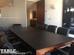 an empty conference room with black leather chairs and a large table in front of it