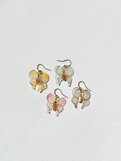 four pairs of flower shaped earrings sitting on top of a white surface with gold ear wires