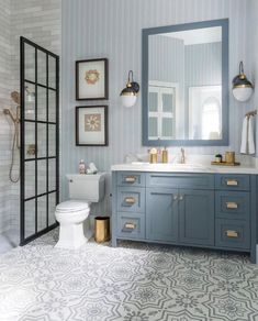 a bathroom with blue cabinets and gold accents on the vanity, toilet and shower stall