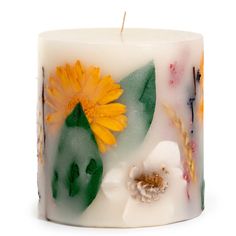 a white candle with yellow flowers and leaves on it's side, against a white background