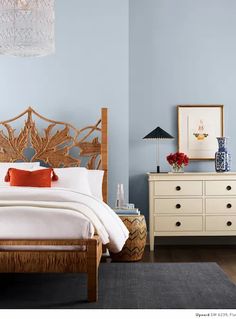 a bedroom with blue walls and white bedding, two nightstands and a dresser