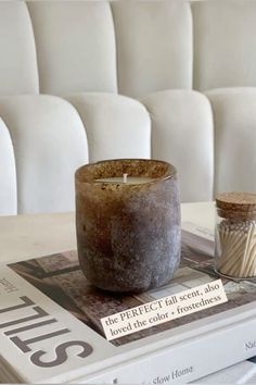 a candle sitting on top of a book next to a glass jar filled with sand