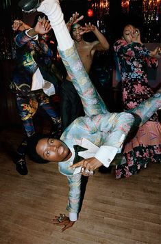 a group of people dancing at a party with one person upside down on the floor