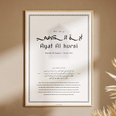 an arabic certificate hanging on the wall next to a potted plant with dried flowers