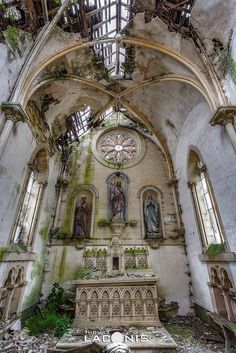 the inside of an abandoned church with stained glass windows and statues on the wall,